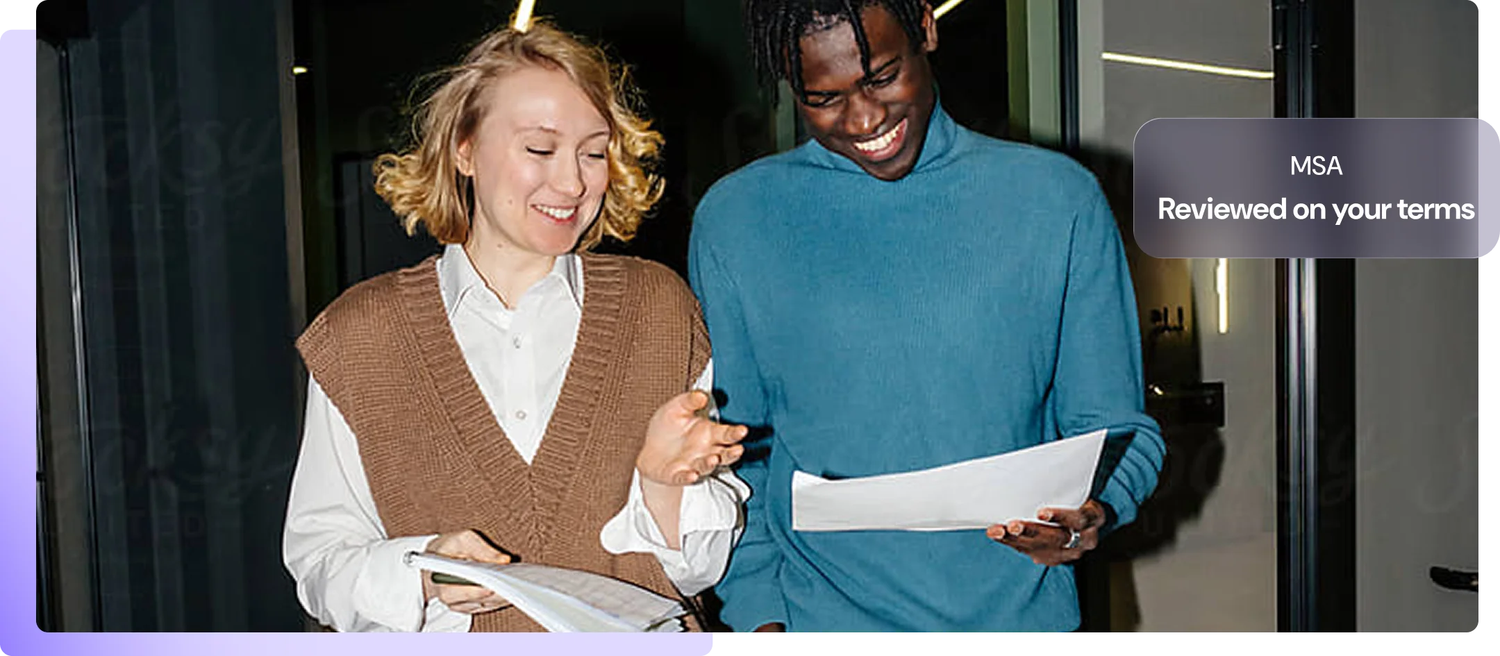 Two colleagues laughing over printed contracts, with an MSA reviewed on their terms
